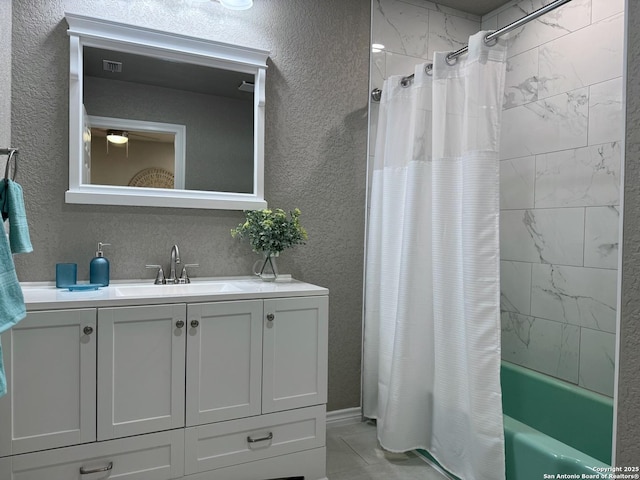 bathroom featuring shower / bath combo with shower curtain, a textured wall, visible vents, and vanity