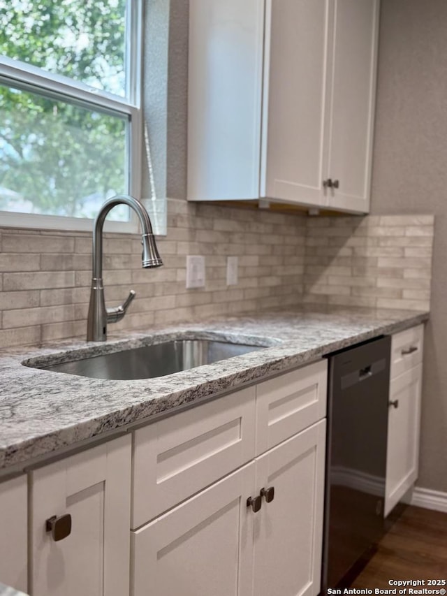 kitchen with a sink, white cabinetry, dark wood-type flooring, backsplash, and dishwashing machine