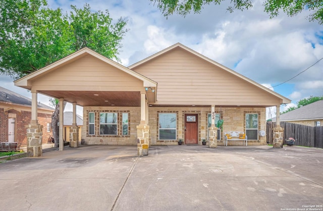 view of front of home with fence, a porch, driveway, and stone siding