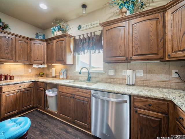 kitchen with stainless steel dishwasher, light stone countertops, dark wood-type flooring, tasteful backsplash, and a sink
