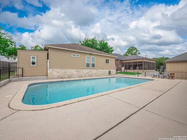 view of pool with fence, a fenced in pool, a patio area, and a sunroom