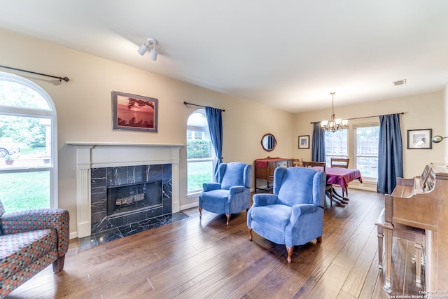 living room with an inviting chandelier, a high end fireplace, wood-type flooring, and visible vents