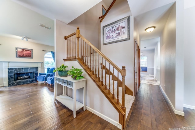 stairway with visible vents, wood-type flooring, baseboards, and a premium fireplace