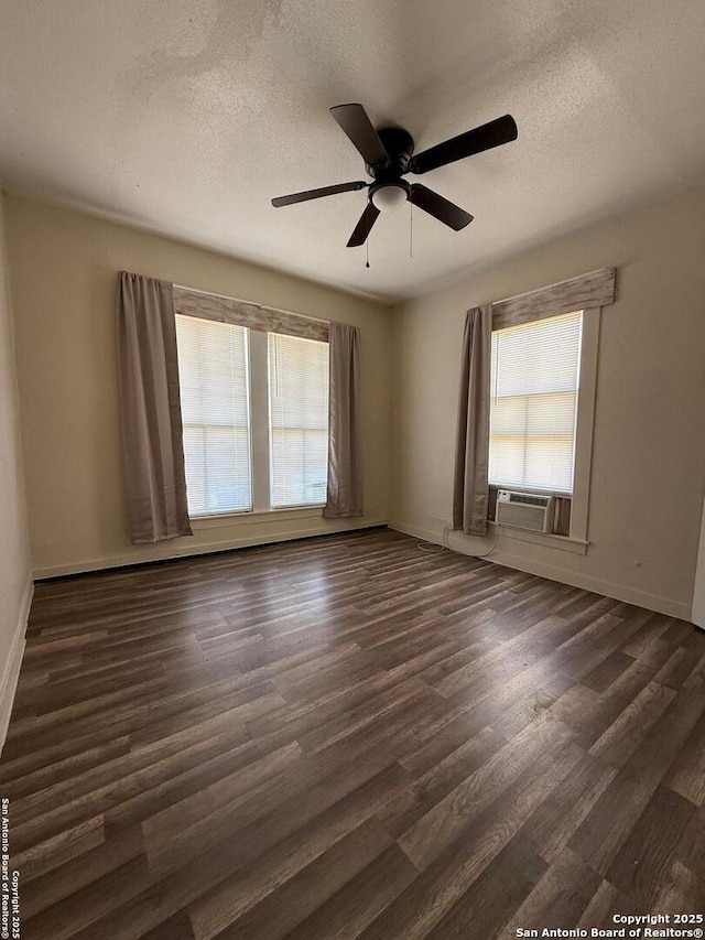 spare room featuring plenty of natural light, cooling unit, dark wood-style floors, and a textured ceiling