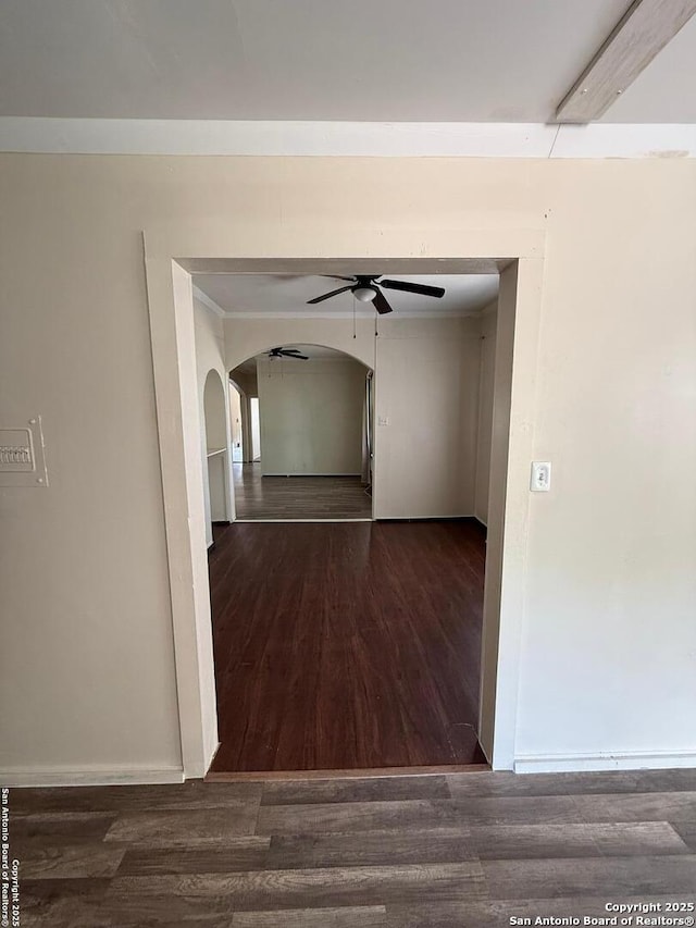 hall with baseboards, arched walkways, and wood finished floors