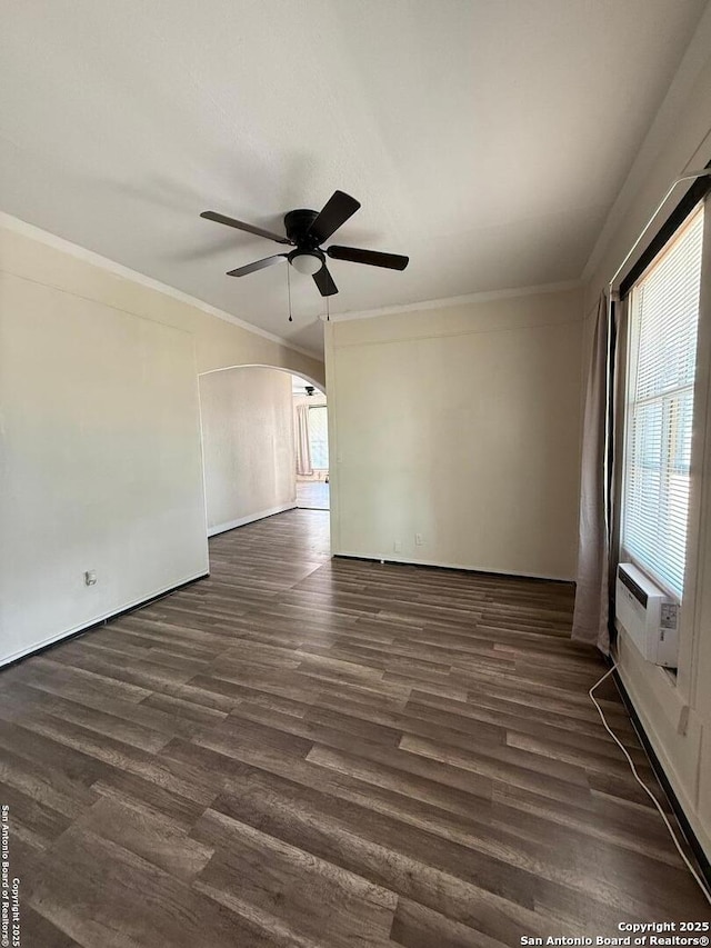 unfurnished room featuring crown molding, a ceiling fan, arched walkways, and dark wood-type flooring