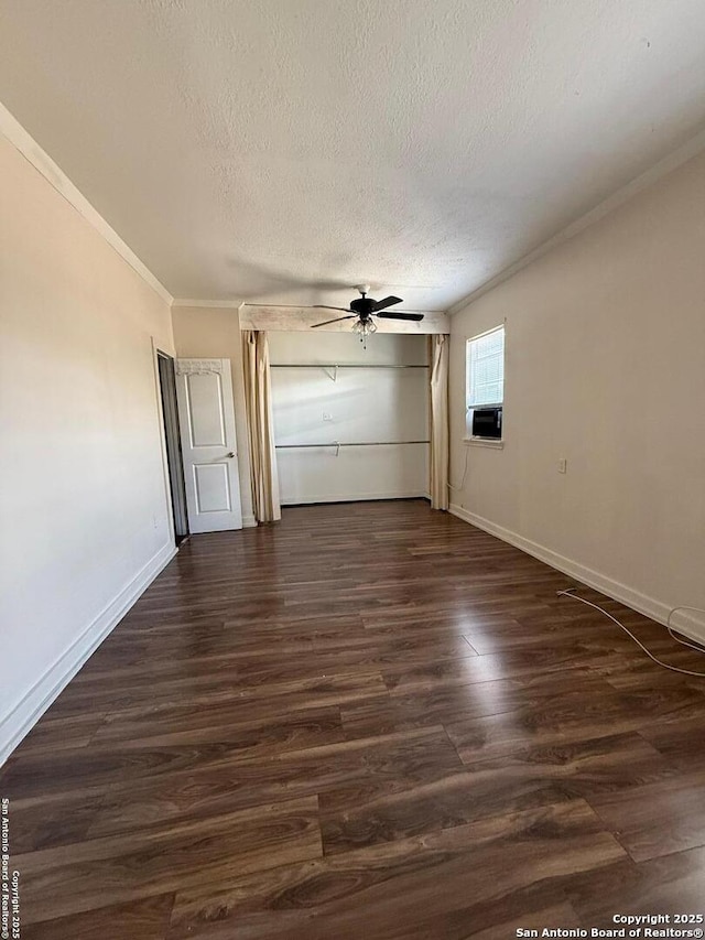 interior space featuring a ceiling fan, dark wood-style flooring, a textured ceiling, baseboards, and ornamental molding