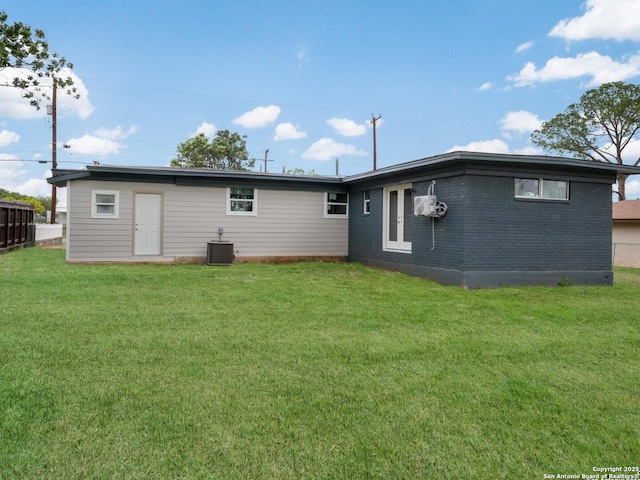 rear view of property featuring central AC unit, a yard, and brick siding