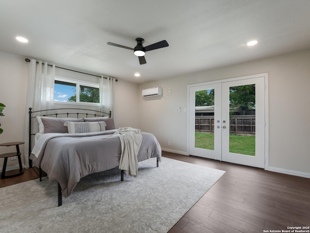 bedroom featuring a wall unit AC, french doors, access to exterior, wood finished floors, and baseboards