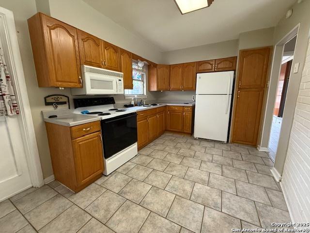 4519 Creekmoor, San Antonio, TX 78220 - kitchen with white appliances, light countertops, brown cabinetry, and light tile patterned flooring
