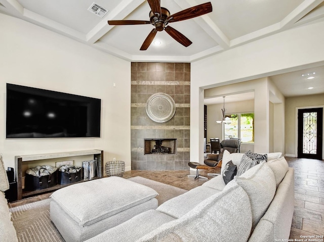 7211 Cresta Bulivar, San Antonio, TX 78256 - living area with a ceiling fan, visible vents, a tiled fireplace, beamed ceiling, and stone tile flooring