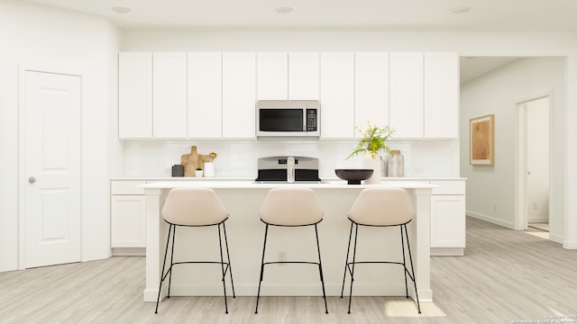 kitchen with tasteful backsplash, stainless steel microwave, a breakfast bar, and range