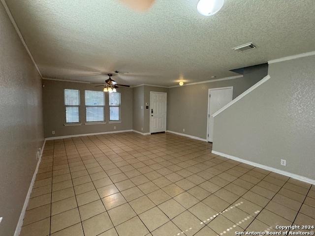 unfurnished living room featuring visible vents, baseboards, ceiling fan, a textured ceiling, and light tile patterned floors