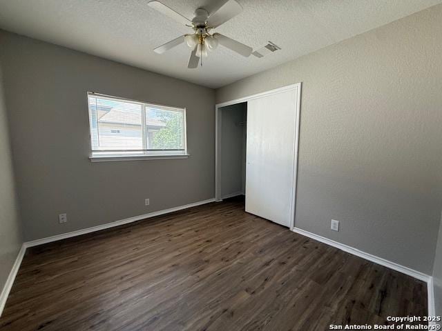 unfurnished bedroom with dark wood-style flooring, baseboards, visible vents, and a closet