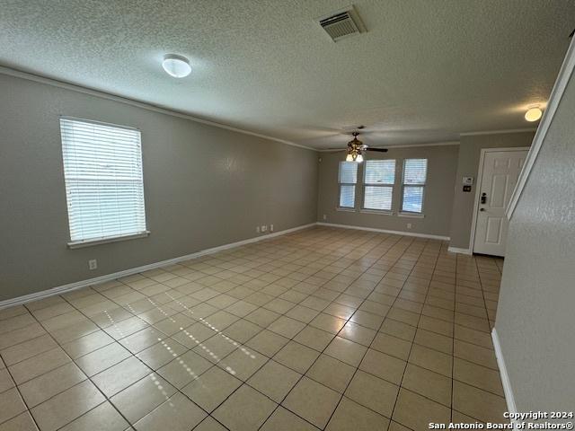 unfurnished room featuring crown molding, ceiling fan, light tile patterned flooring, and visible vents