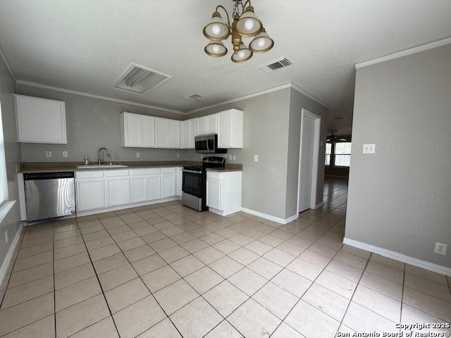 kitchen featuring appliances with stainless steel finishes, a sink, baseboards, visible vents, and ornamental molding