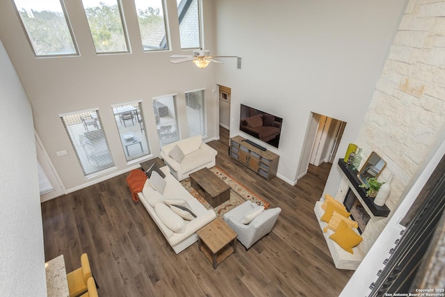 living room featuring ceiling fan, a wealth of natural light, wood finished floors, and a towering ceiling