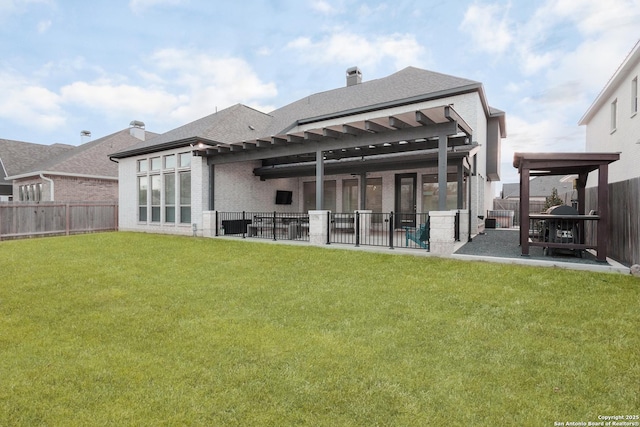 back of house with a yard, a patio, brick siding, and a fenced backyard
