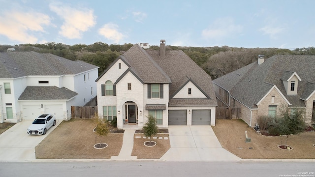 french country home with fence, driveway, a shingled roof, and a garage