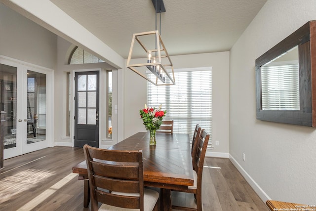 dining area with a textured ceiling, baseboards, french doors, and wood finished floors