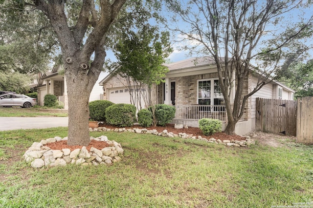 view of front facade with a garage, a front lawn, fence, and covered porch