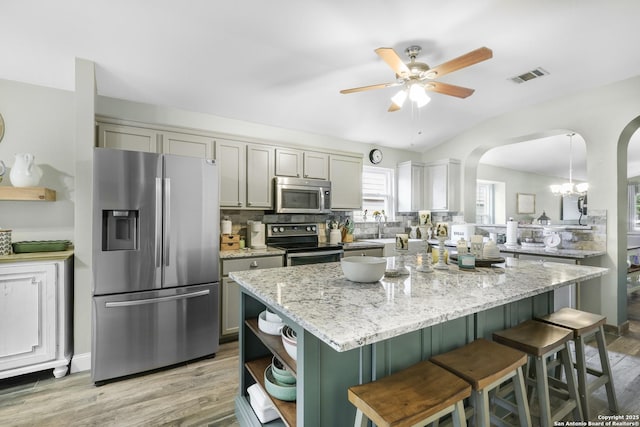 kitchen with visible vents, open shelves, a center island, arched walkways, and stainless steel appliances