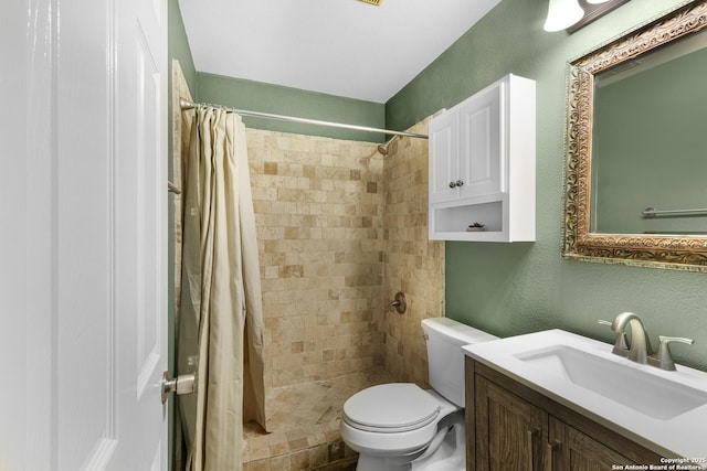 bathroom featuring vanity, a textured wall, toilet, and tiled shower