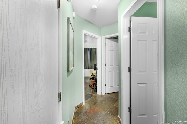 hallway with a textured wall and stone tile flooring