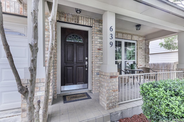 doorway to property with a porch and stone siding