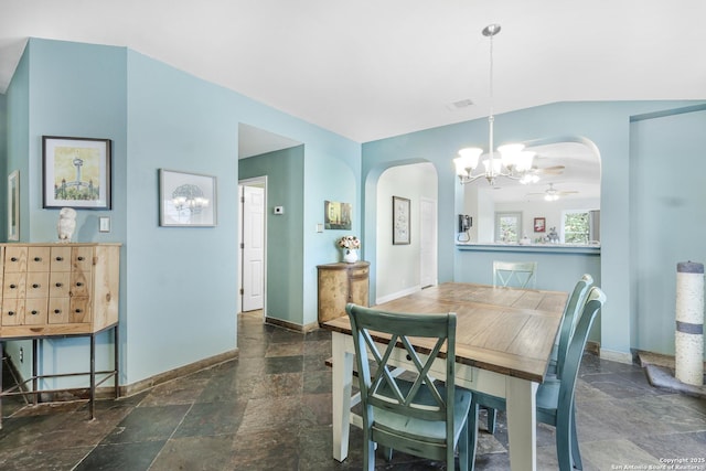 dining room with arched walkways, baseboards, lofted ceiling, visible vents, and stone tile flooring