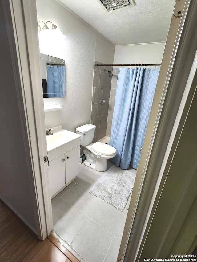 4802 Castle Brg, San Antonio, TX 78218 - full bathroom with a textured ceiling, vanity, tiled shower, a textured wall, and toilet