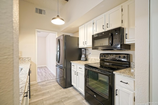 kitchen with white cabinets, light stone countertops, visible vents, and black appliances