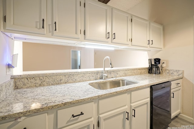 kitchen featuring white cabinetry, light stone counters, a sink, and dishwasher