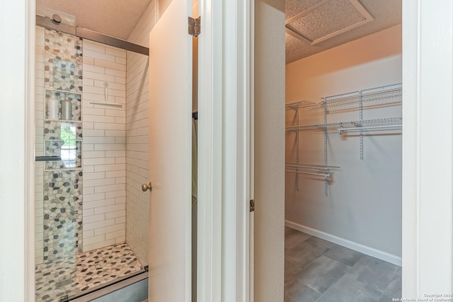 bathroom with baseboards, a walk in closet, and a shower stall