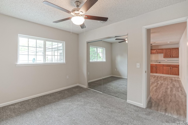 unfurnished bedroom featuring baseboards, a closet, a textured ceiling, and light colored carpet