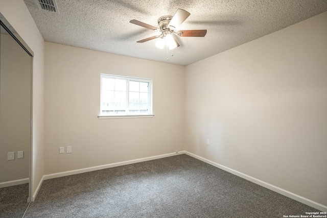 unfurnished room featuring ceiling fan, a textured ceiling, visible vents, baseboards, and dark carpet