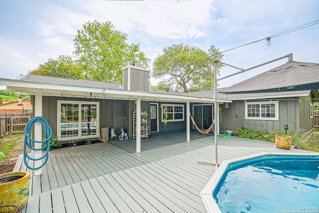 back of house with fence, board and batten siding, a chimney, and a deck