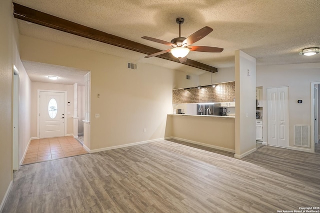 unfurnished living room with visible vents, a textured ceiling, ceiling fan, and wood finished floors