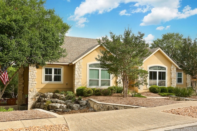 view of front of home featuring stone siding, roof with shingles, and stucco siding