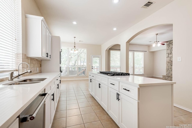 kitchen with decorative backsplash, a ceiling fan, visible vents, gas stovetop, and a sink