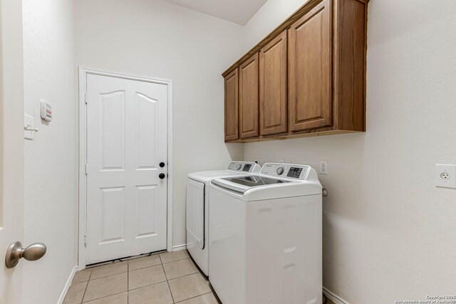 clothes washing area with independent washer and dryer, baseboards, light tile patterned floors, and cabinet space
