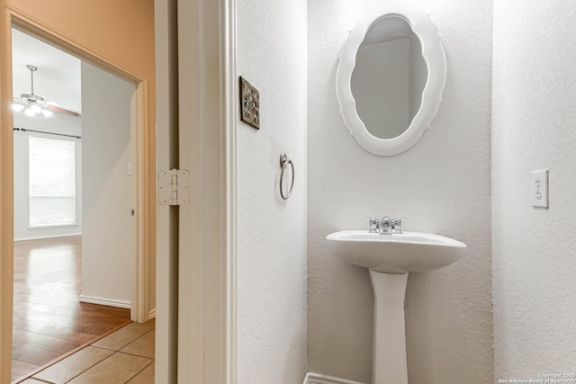 bathroom with tile patterned floors, a textured wall, and ceiling fan