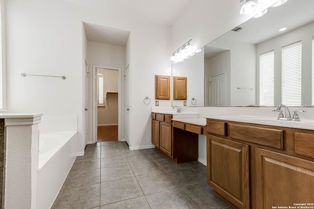 full bathroom featuring visible vents, a garden tub, double vanity, tile patterned floors, and a sink