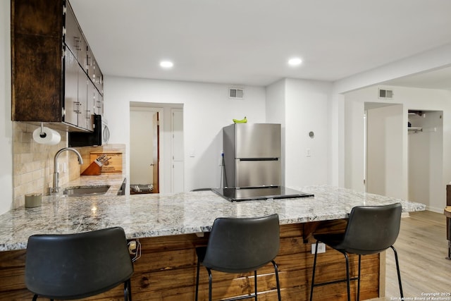 kitchen with stainless steel appliances, visible vents, a sink, and a peninsula