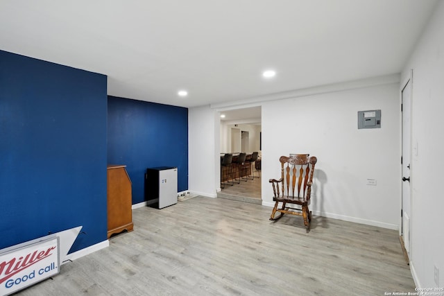 sitting room with baseboards, electric panel, recessed lighting, and wood finished floors