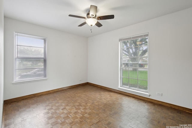 unfurnished room featuring baseboards, a ceiling fan, and a wealth of natural light