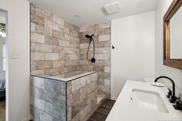 bathroom with baseboards, tiled shower, and vanity