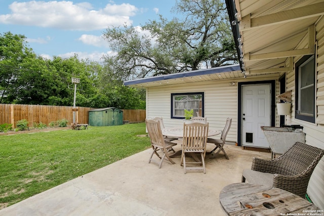 view of patio featuring a fenced backyard, outdoor dining space, an outbuilding, and a shed