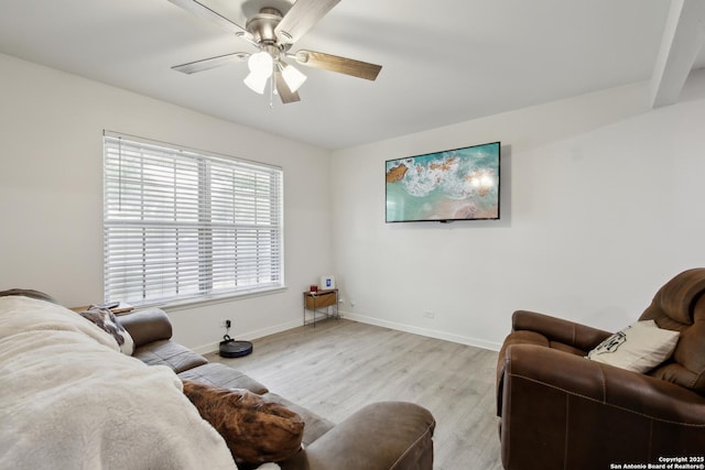 living area with light wood-type flooring, a ceiling fan, and baseboards