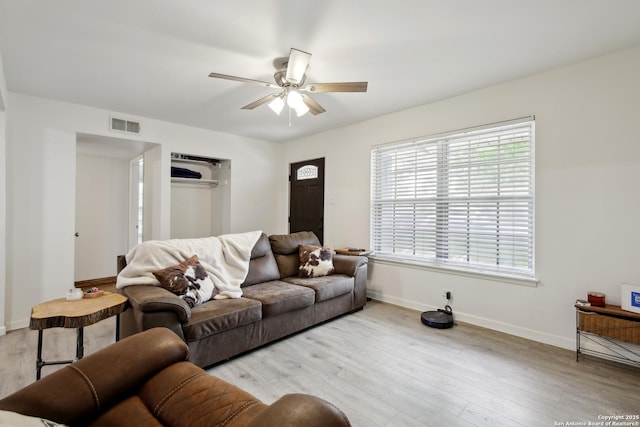 living area with light wood-style floors, baseboards, a ceiling fan, and visible vents